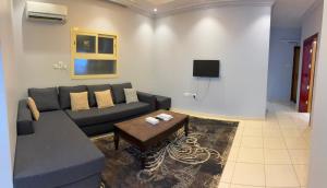 a living room with a couch and a table at Al Samia economy apartment in Baljurashi