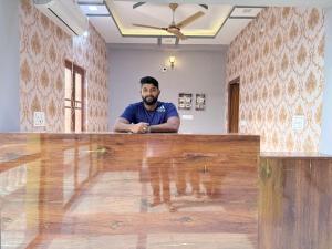 a man standing behind a large wooden table at Hotel Drip inn JNK in Lucknow