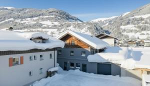 a house covered in snow with mountains in the background at Bramberg Hideaway mit großer Terrasse in Größing