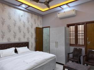a bedroom with a bed and two chairs and a fan at Hotel Drip inn JNK in Lucknow