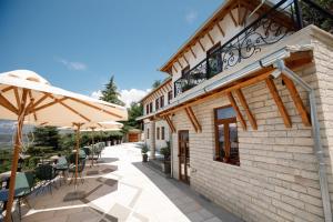a patio with chairs and umbrellas next to a building at Vila Mantho in Gjirokastër