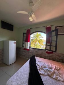 a bedroom with a refrigerator and a window with a palm tree at Recanto do sol in Mangaratiba