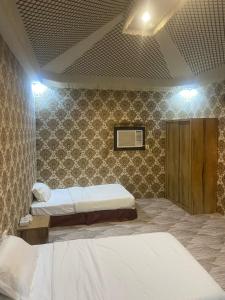 a bedroom with two beds in a room with a wall at منتجع اغصان الشفا in Ash Shafa