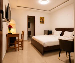 a bedroom with a bed and a table and a desk at Hotel Nana in Abidjan +52 photos