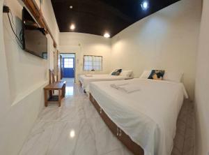 a bedroom with two beds and a television on the wall at 龍磐1號民宿 全家出遊首選1至12人包棟 均一價 免爬梯獨棟平房 三間獨立套房 寬敞庭院可烤肉 in Eluan