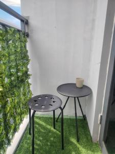 a table and two stools on a balcony with a plant at Casa Hiraya - Shore 2 Tower 2 in Manila