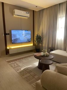 a living room with a tv and a couch and a table at أواسِيس Oasis Stay in Al Muḩassin +5 photos