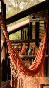 a hammock hanging on a porch with a house at Pousada Aconchego do Rosa - Centrinho do Rosa in Praia do Rosa