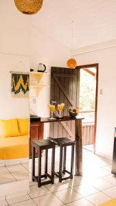 a kitchen with a table and two stools at Pousada Aconchego do Rosa - Centrinho do Rosa in Praia do Rosa