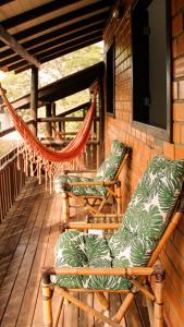 a porch with two chairs and a hammock on it at Pousada Aconchego do Rosa - Centrinho do Rosa in Praia do Rosa