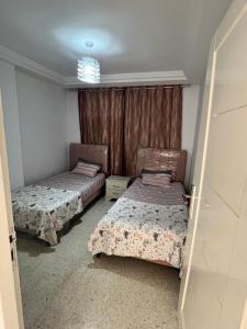 a bedroom with two beds and a window at Appartement 2 chambres à 250m de la plage, propre & bien équipé in Monastir