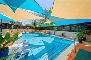 a large swimming pool with a large blue umbrella at Hidden Gem The Moroccan - by ZenBreak in Christ Church +20 photos