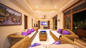 a living room with wicker furniture and purple pillows at Orchid House Pattaya, Totally Private Pool in Pattaya South