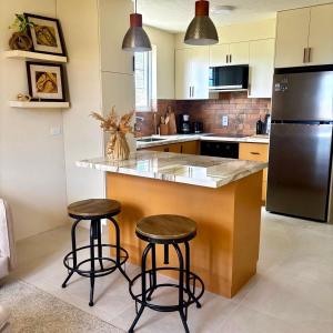 a kitchen with two bar stools and a refrigerator at Cazuria - by ZenBreak in Saint George