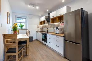 a kitchen with white cabinets and a stainless steel refrigerator at LU-KA Apartamenty in Swornegacie