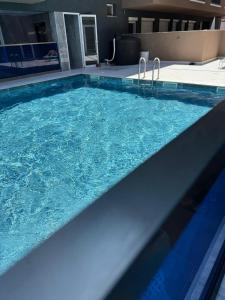 a large pool with blue water in a building at Premium Studio Family in Paralia Katerinis