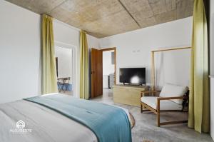a bedroom with a bed and a chair and a television at OceanLand - Santa Cruz in Santa Cruz