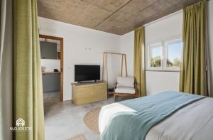 a bedroom with a bed and a tv and a chair at OceanLand - Santa Cruz in Santa Cruz
