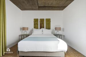 a bedroom with a large white bed with two lamps at OceanLand - Santa Cruz in Santa Cruz