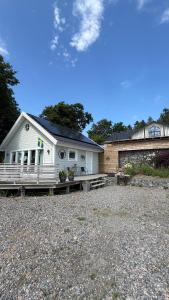 a white house with a porch and a stone yard at Reinholds Gästhus in Kareby