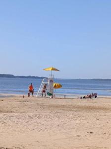 people on a beach with an umbrella and a lifeguard chair at Hotel Plaza in Concepción del Uruguay