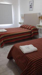 two beds in a hotel room with towels on them at Hotel Plaza in Concepción del Uruguay