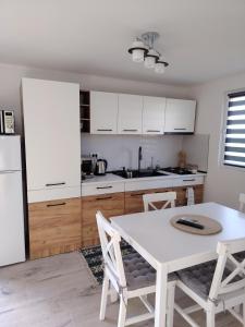 a kitchen with white cabinets and a white table and chairs at Casa Joe in Corbu
