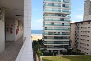 a tall building with a beach in the background at Apto Gonzaga a 20m da praia -Ar Split & Pet Friendly in Santos