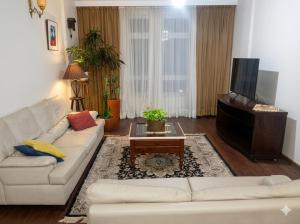 ein Wohnzimmer mit einem weißen Sofa und einem Fernseher in der Unterkunft Apartamento Gonzaga Santos in Santos