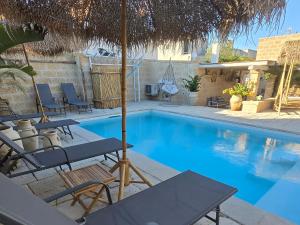 a swimming pool with chairs and an umbrella at LA PIGNA BLU CasaVacanza con Piscina in Botrugno