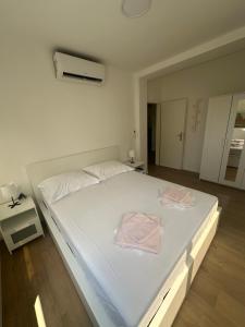 a large white bed with two pink towels on it at Apartmani Paula in Makarska