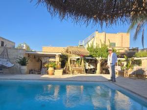 a man standing next to a swimming pool at LA PIGNA BLU CasaVacanza con Piscina in Botrugno
