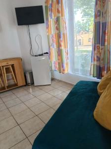 a room with a bed and a television and a tiled floor at Elo Apartman in Csokonyavisonta