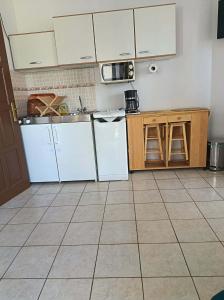 a kitchen with white cabinets and a tile floor at Elo Apartman in Csokonyavisonta +3 photos