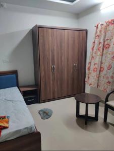 a bedroom with a cabinet and a bed and a table at Rail connect hotel statue of unity in Kevadia