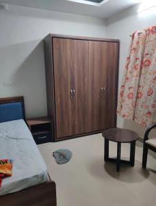 a bedroom with a bed and a cabinet and a table at Rail connect hotel statue of unity in Kevadia