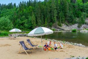 a group of children sitting under an umbrella on a beach at Hotel Litworowy Staw in Białka Tatrzańska