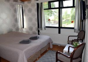 a bedroom with a bed and two chairs and a window at Hotel Hanhi in Lapinjärvi +20 photos