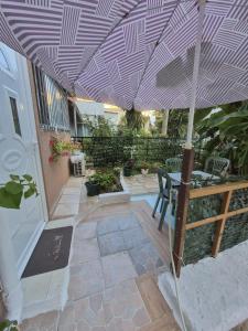 a patio with an umbrella and a table and chairs at Saranda Garden Rooms in Sarandë