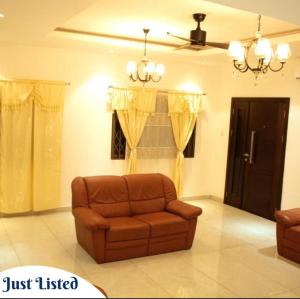 ein Wohnzimmer mit braunem Sofa und einem Fenster in der Unterkunft Omane Homes in Cape Coast + 1 Foto