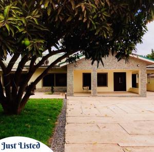 ein Haus mit einem Baum davor in der Unterkunft Omane Homes in Cape Coast