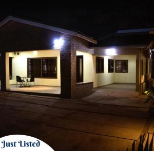 ein nachts beleuchtetes Haus mit einem Tisch im Freien in der Unterkunft Omane Homes in Cape Coast