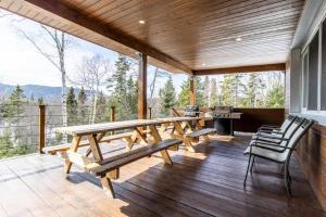 a wooden deck with a picnic table and chairs at Welcome to La Cabine de Charlevoix in Petite-Rivière-Saint-François