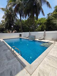 a swimming pool with blue water and palm trees at Villa Clasic Comfort in Navalur