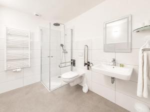 a white bathroom with a sink and a toilet at Hotel Kaiserhof in Lehrte +6 photos