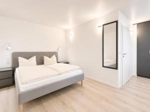 a white bedroom with a bed and a mirror at Hotel Kaiserhof in Lehrte