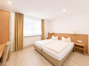 a bedroom with a large white bed and a window at Hotel Kaiserhof in Lehrte