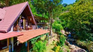a house with a red roof next to a river at Cinnamon River Cabana in Ella