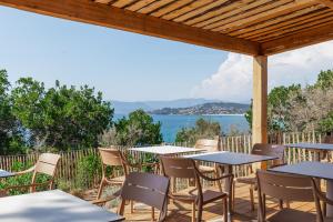 a patio with tables and chairs and a view of the water at La maison de simon in Pietrosella