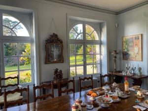 a dining room with a table and three windows at Manoir Mer & Pins in Fouesnant